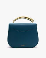 Handbag with a curved metallic handle on top.