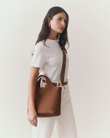 Person holding a handbag in one hand, wearing a t-shirt and pants.