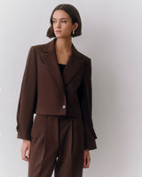 Person wearing a suit jacket and trousers looking to the side.