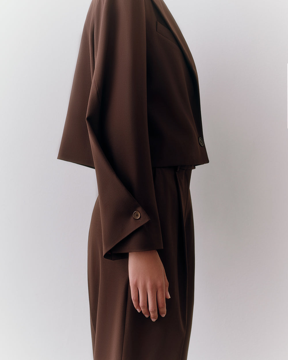 Person in side profile wearing a suit with long sleeves
