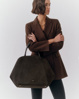 Person in a blazer holding a large geometric handbag