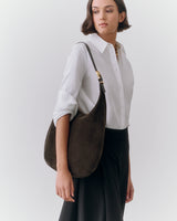 Person wearing a shirt and skirt, holding a shoulder bag.