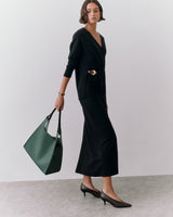 Person wearing a long dress with belt, holding a large handbag, and wearing heels.