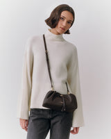 Person wearing a sweater and jeans with a shoulder bag.