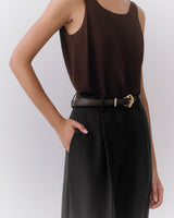 Person wearing a sleeveless top with trousers and a belt.