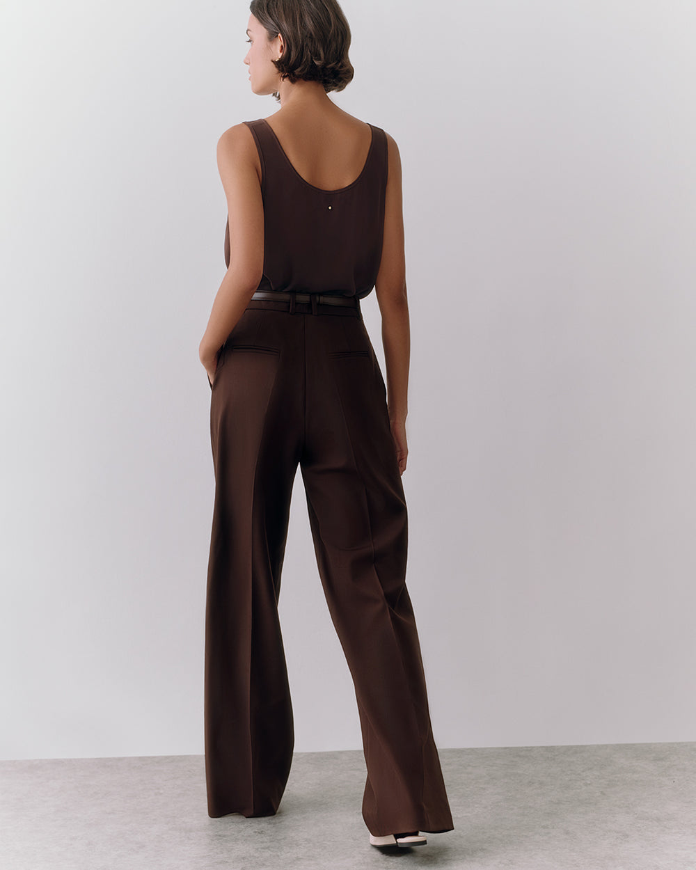 Person wearing a sleeveless top and high-waisted pants facing away