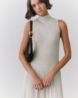 A person in a sleeveless dress with a shoulder bag.