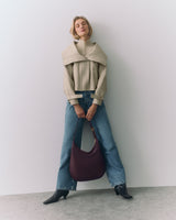 Person posing with a large handbag, wearing jeans, ankle boots, and a structured jacket.