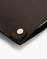 Textured leather laptop sleeve with a metallic button on a corner.