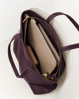 Open tote bag with a laptop and a pouch inside, placed on a chair.