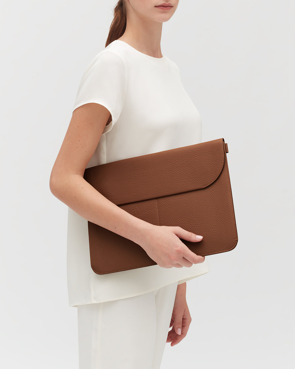 Person holding a large leather laptop sleeve