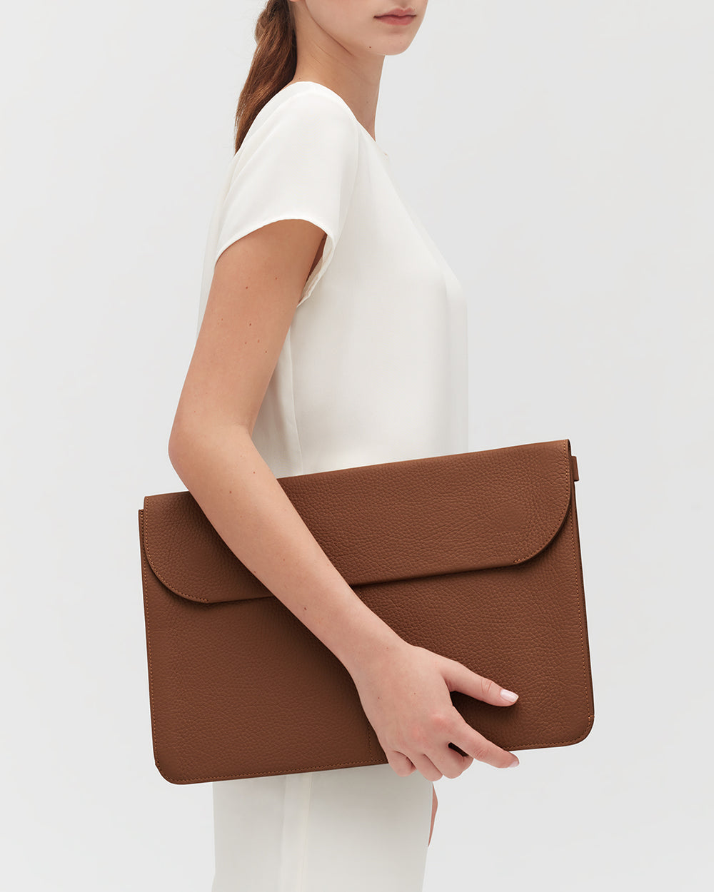 Person holding a large textured clutch under their arm.