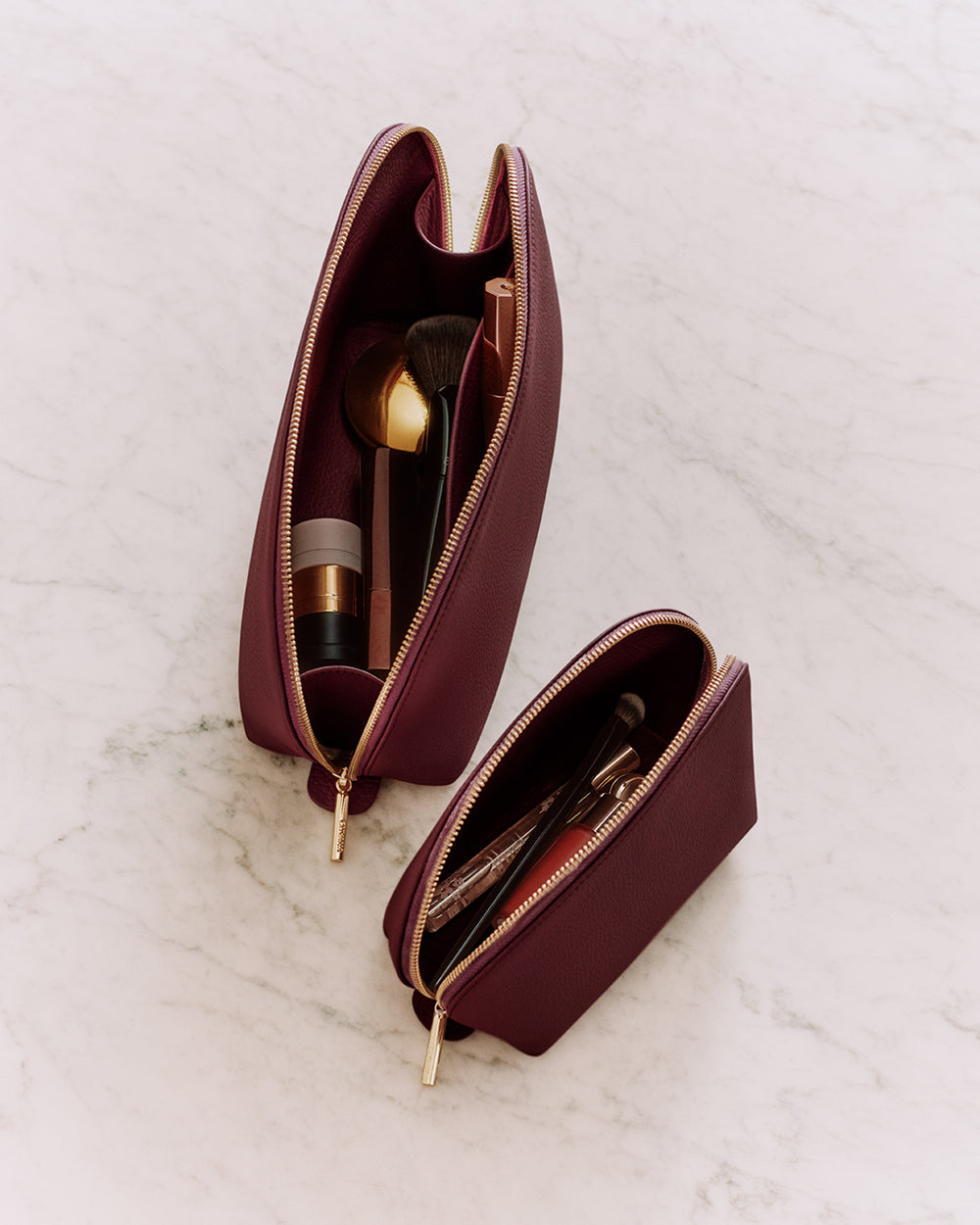Two open makeup bags with brushes and cosmetic products inside.