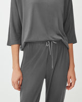 Person wearing a T-shirt and drawstring pants, standing with hands at sides.