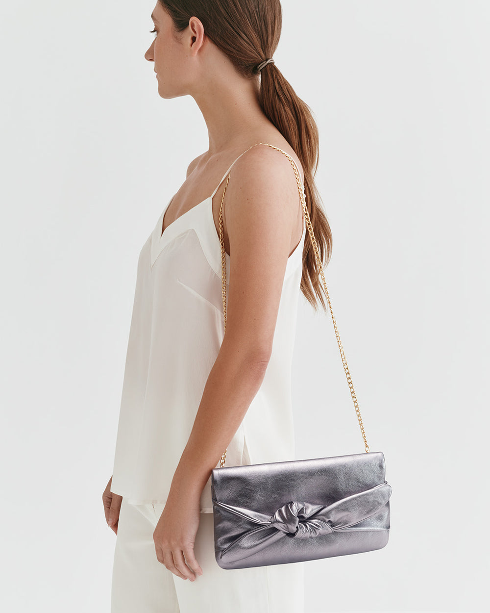 Woman standing with a handbag over her shoulder.