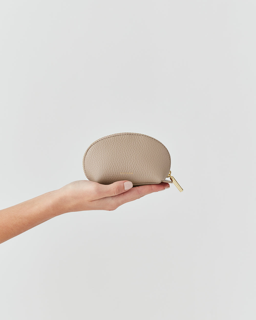 Hand holding a small zippered pouch against a plain background.