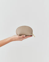 Hand holding a small zippered pouch against a plain background.