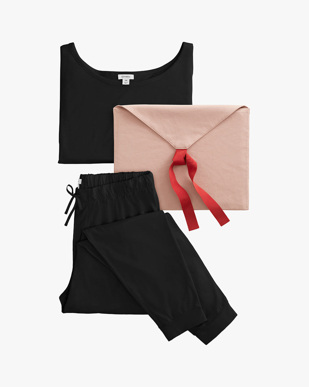 Top, pants, and a gift envelope with ribbon arranged on solid background.