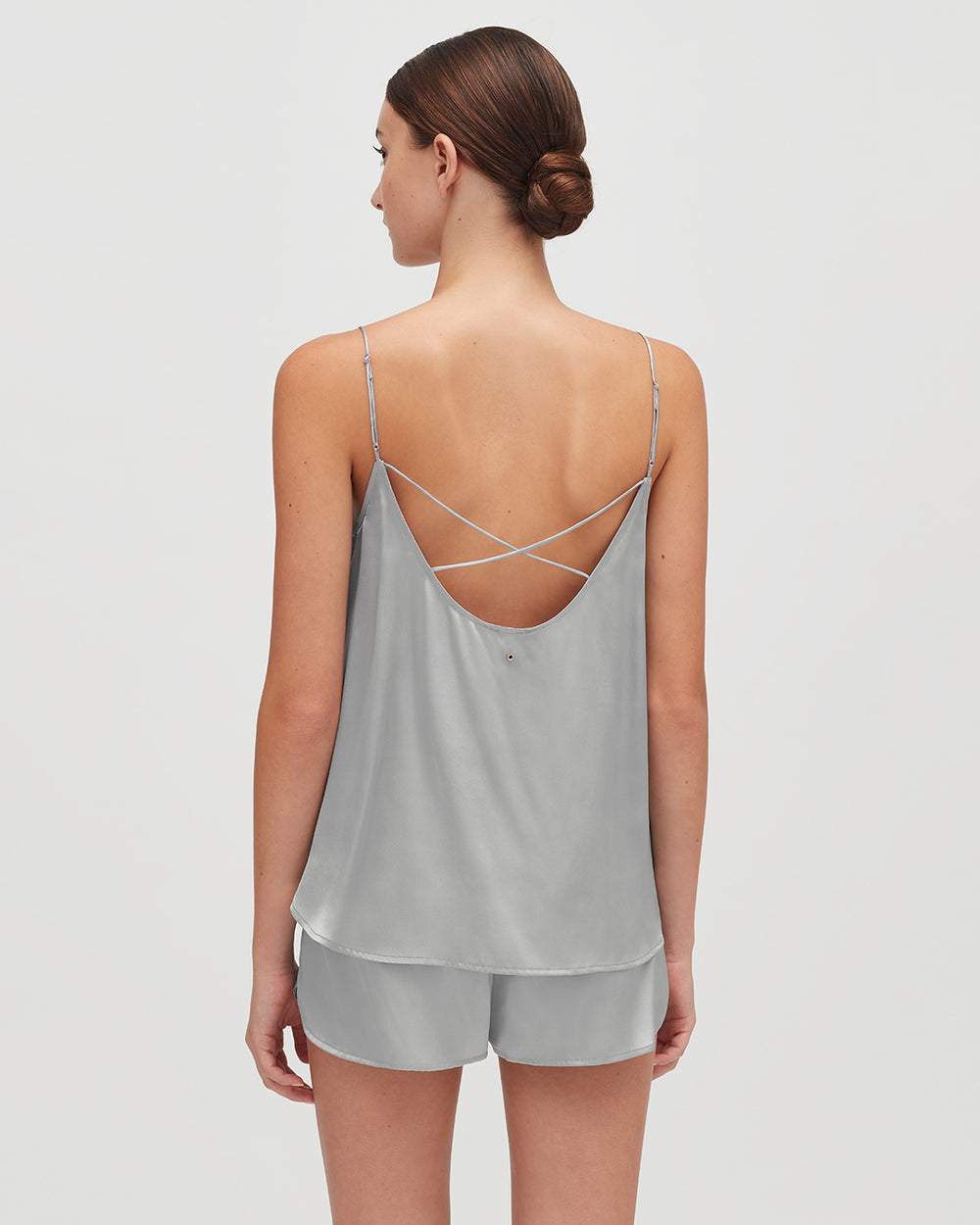 Woman standing with her back to the camera wearing a tank top and shorts.