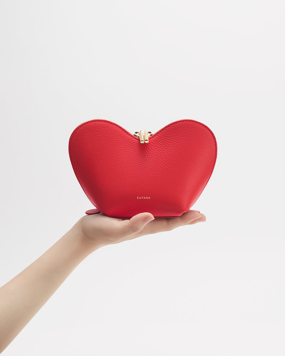 Hand holding heart-shaped pouch with metal clasp