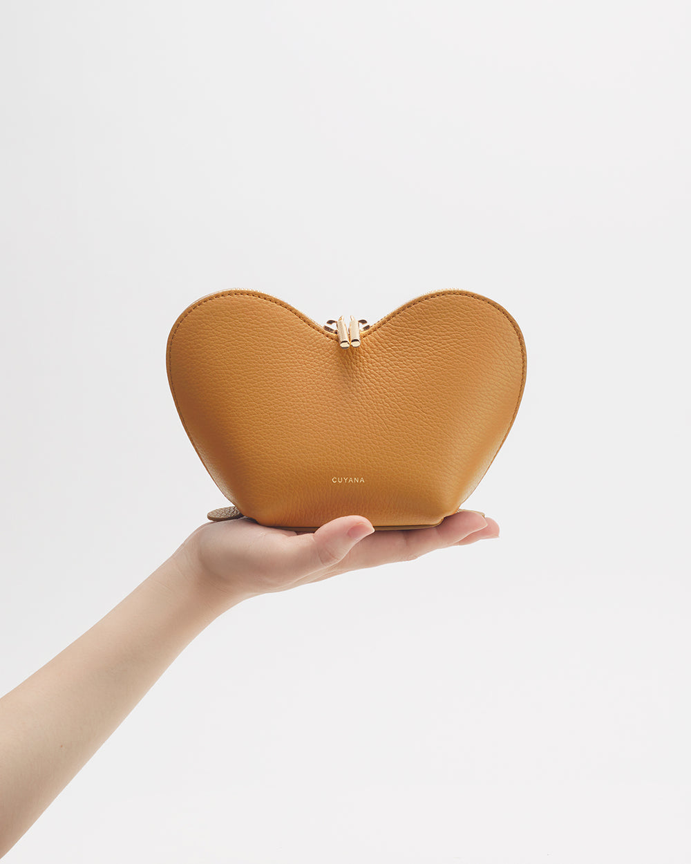 Hand holding a heart-shaped clutch purse.