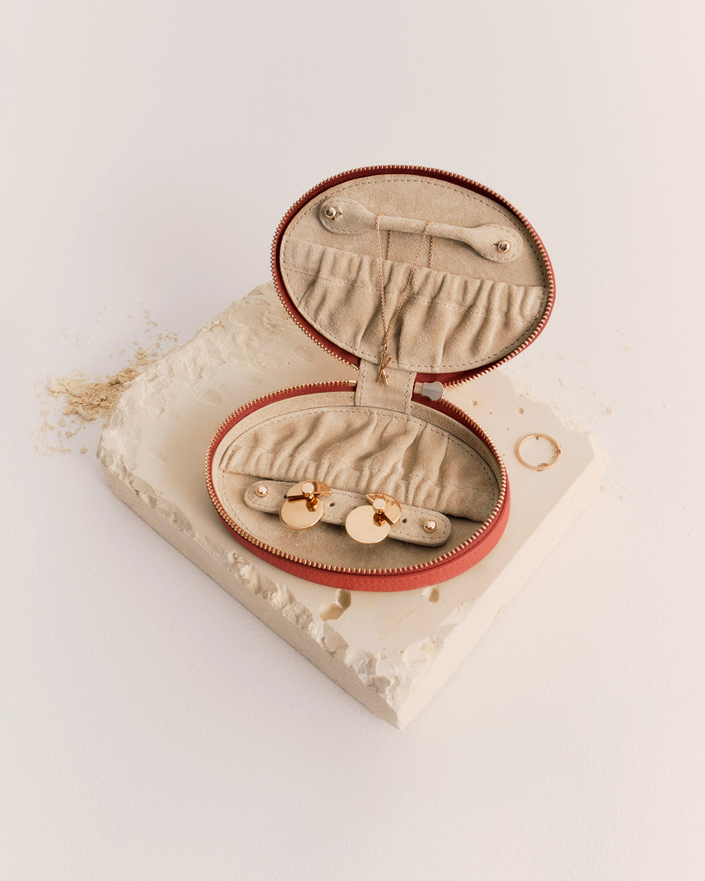 Oval jewelry case open on a textured surface