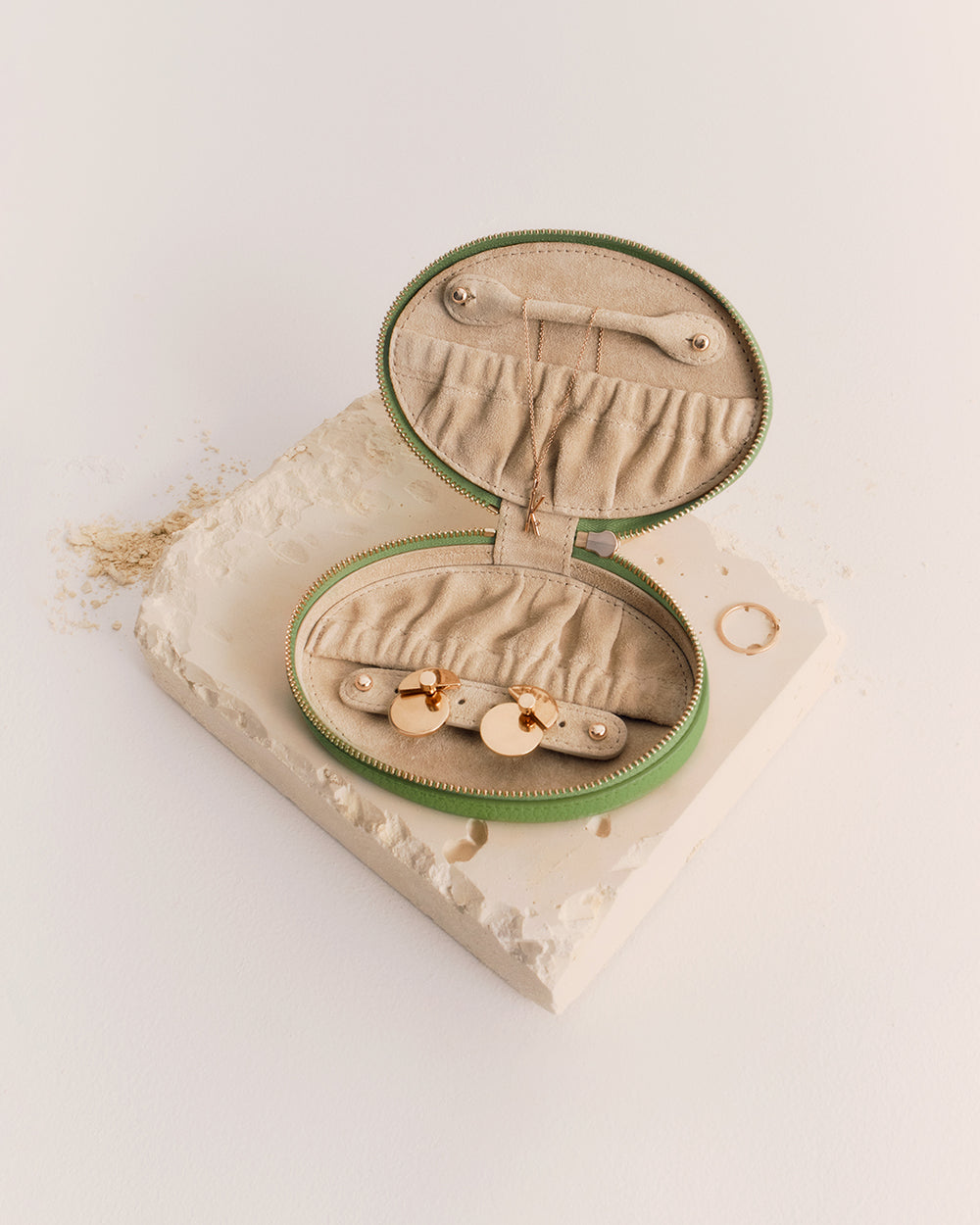 Oval jewelry case with open lid on textured surface.