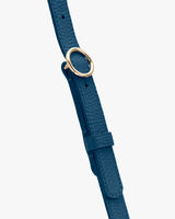 Close-up of a textured strap with a round metal buckle.