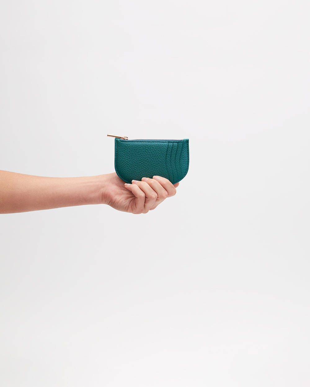 Hand holding a small half-moon wallet against a plain background
