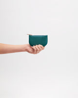 Hand holding a small half-moon wallet against a plain background
