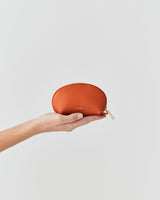 Hand holding a small pouch against plain background.