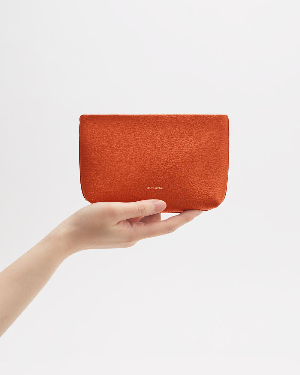 Hand holding a small pouch against a plain background.