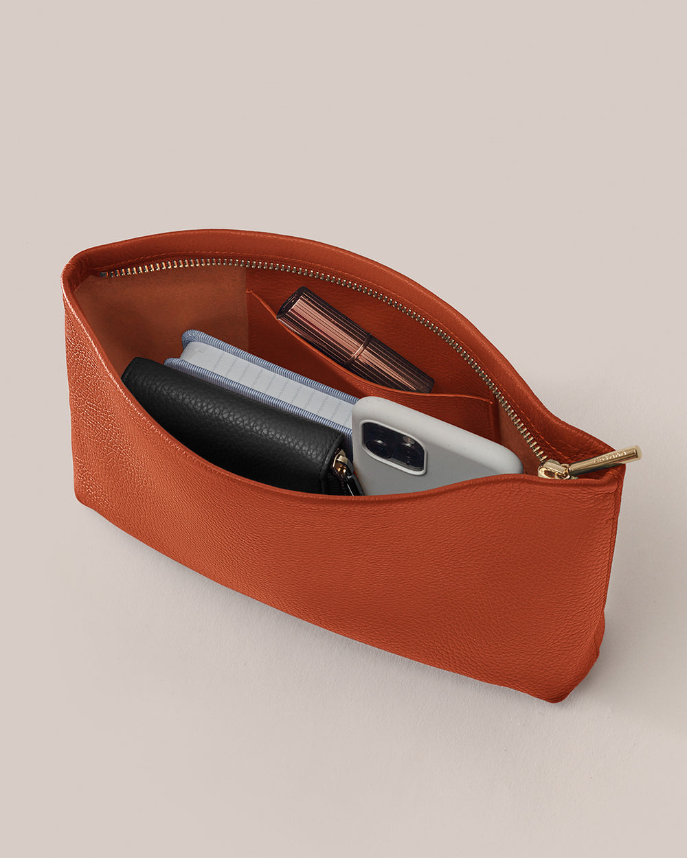 Open pouch with phone, wallet, book, and lipstick inside.
