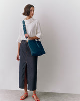 Person wearing long skirt, top, sandals, holding a shoulder bag