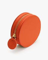 Round zippered pouch with circular tag attached.