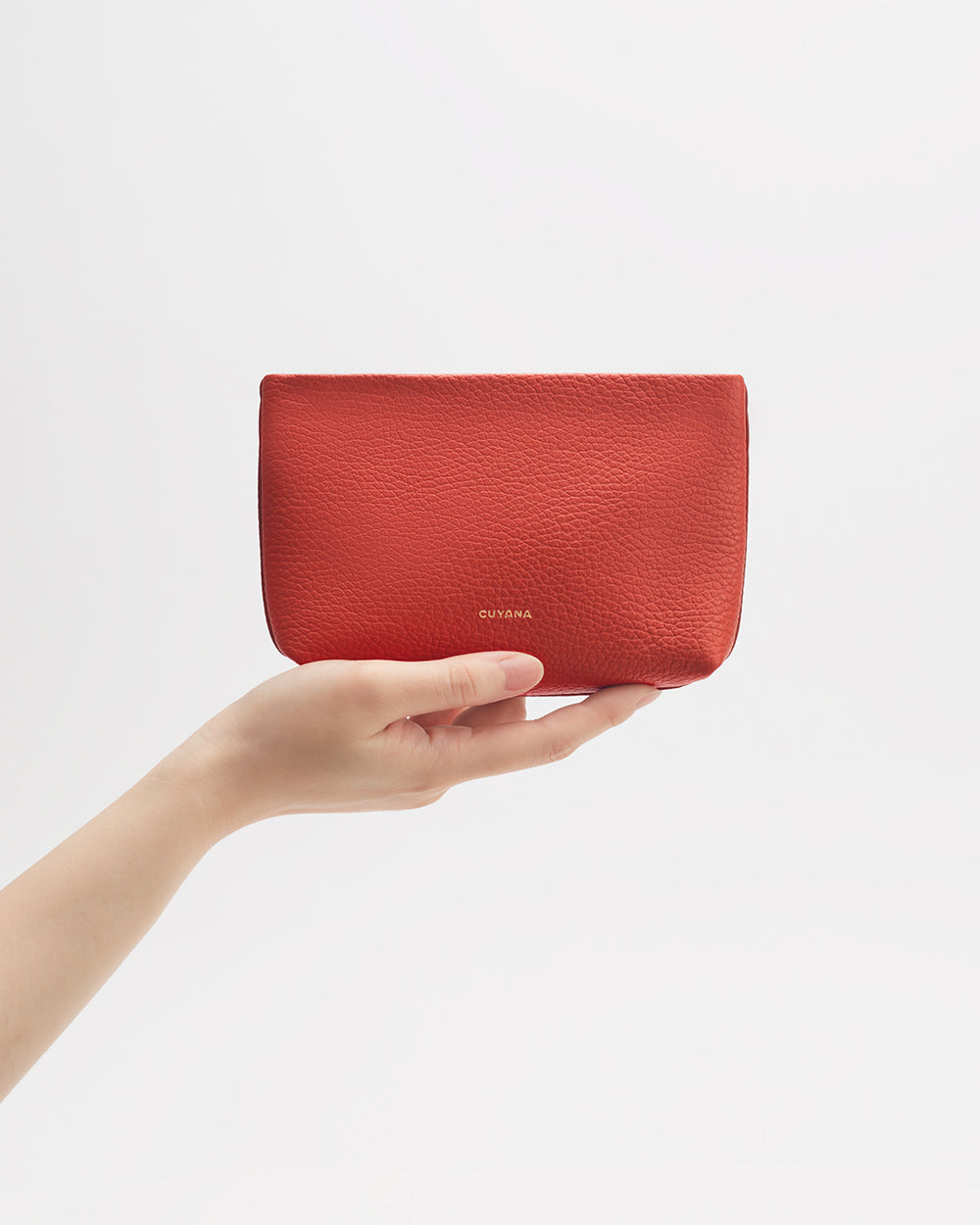 Hand holding a small leather pouch with a minimalist design.