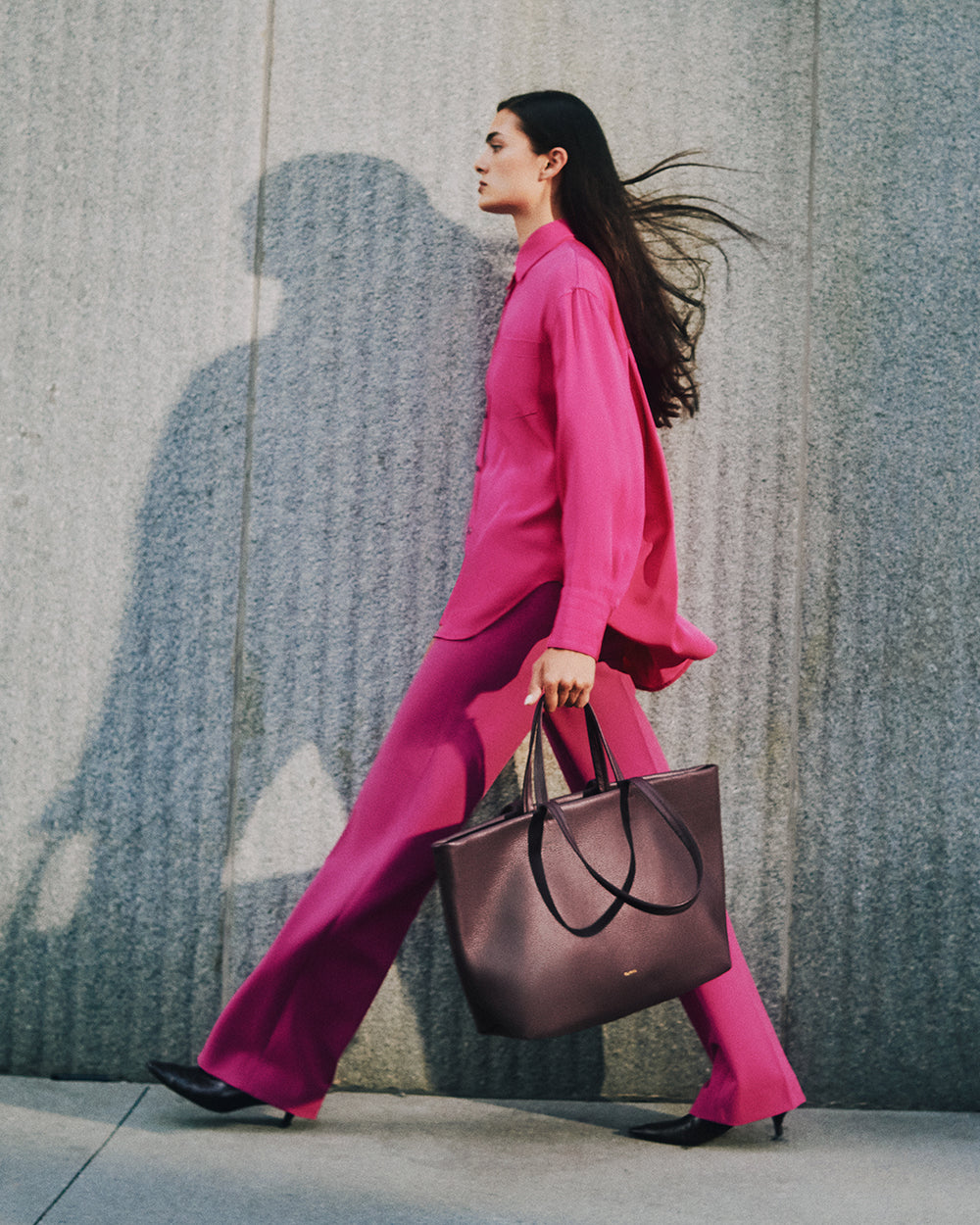 Person walking with large tote bag against textured wall