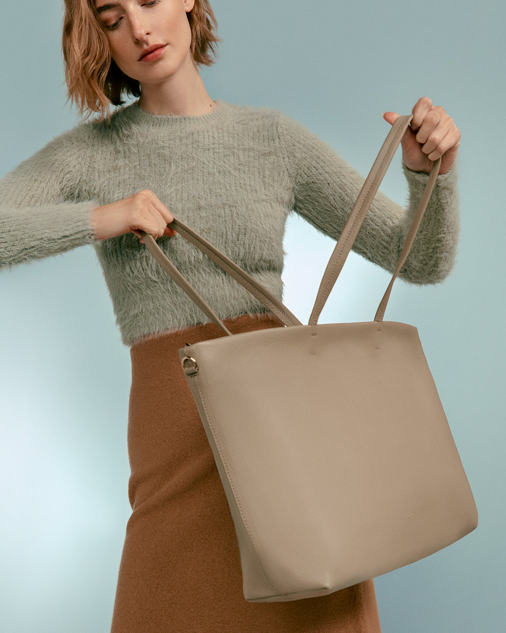 Person holding a large handbag with both hands