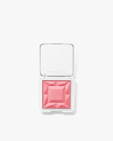 Makeup blush compact with geometric design on powder surface.