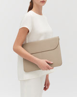 Person holding a large leather laptop sleeve