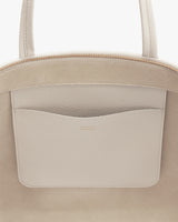 Close-up of a handbag with a zip top and external pocket.