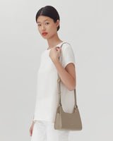 Woman standing with a purse on her shoulder.