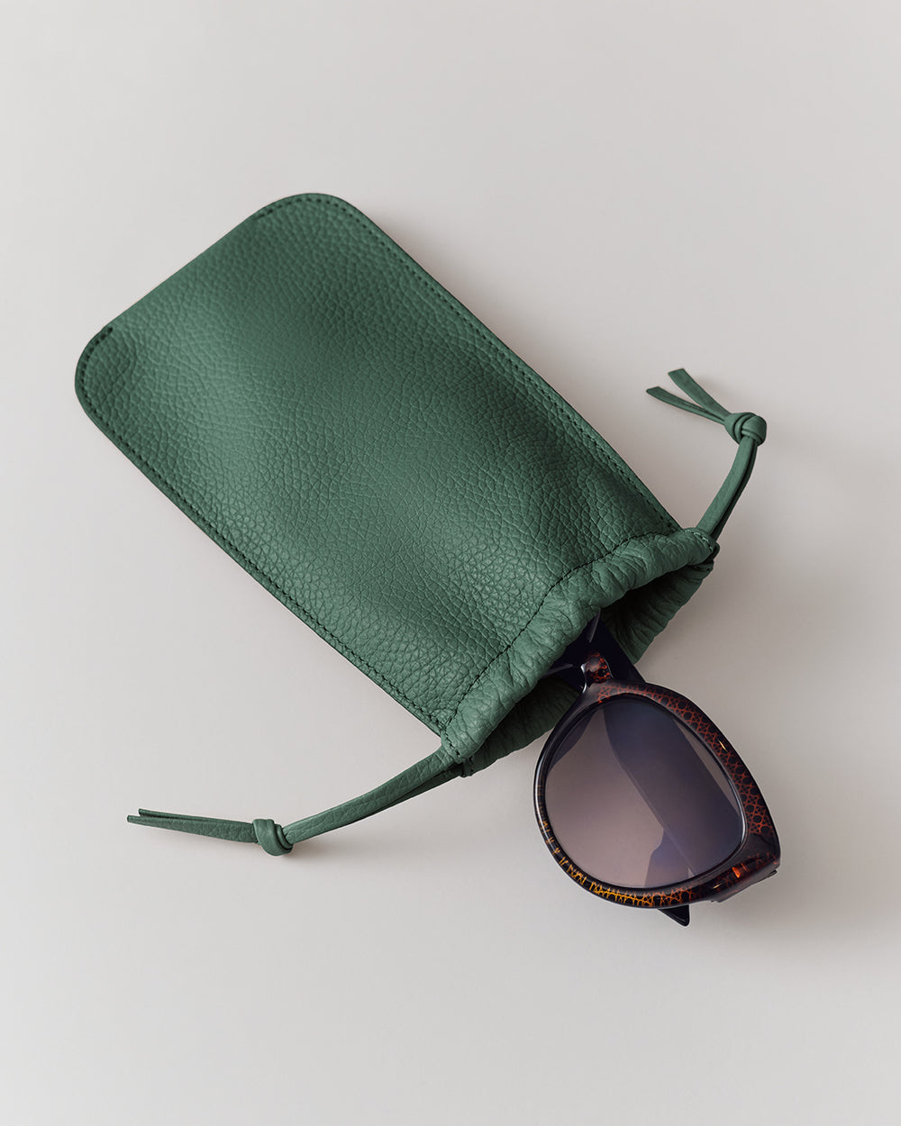 Sunglasses partially inside a textured pouch with drawstrings.