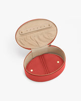 Open oval jewelry case with zipper and fabric lining inside.