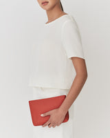 Person holding a pouch, wearing a short-sleeve top.