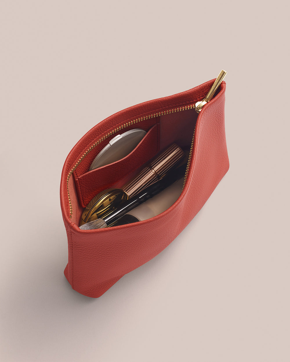 Small pouch with a zip, containing a compact, a brush, and eyeglasses.