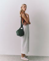 Person standing with handbag, wearing sleeveless top and long skirt.