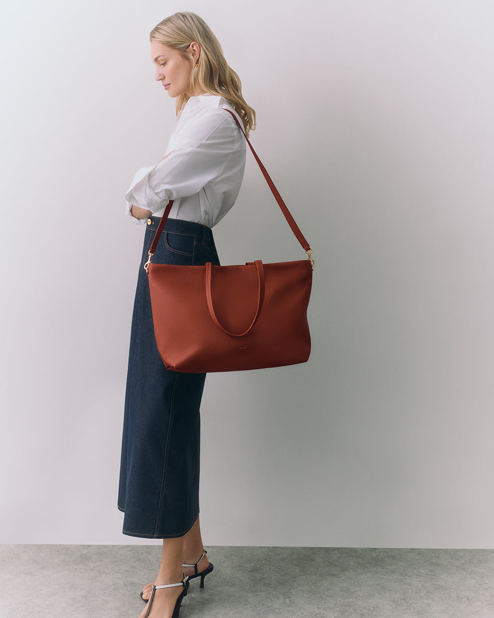 Person carrying a large shoulder bag while standing against a plain background.