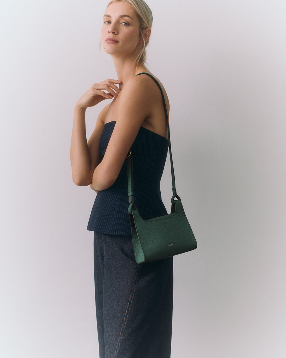 Person in a strapless top holding a shoulder bag.