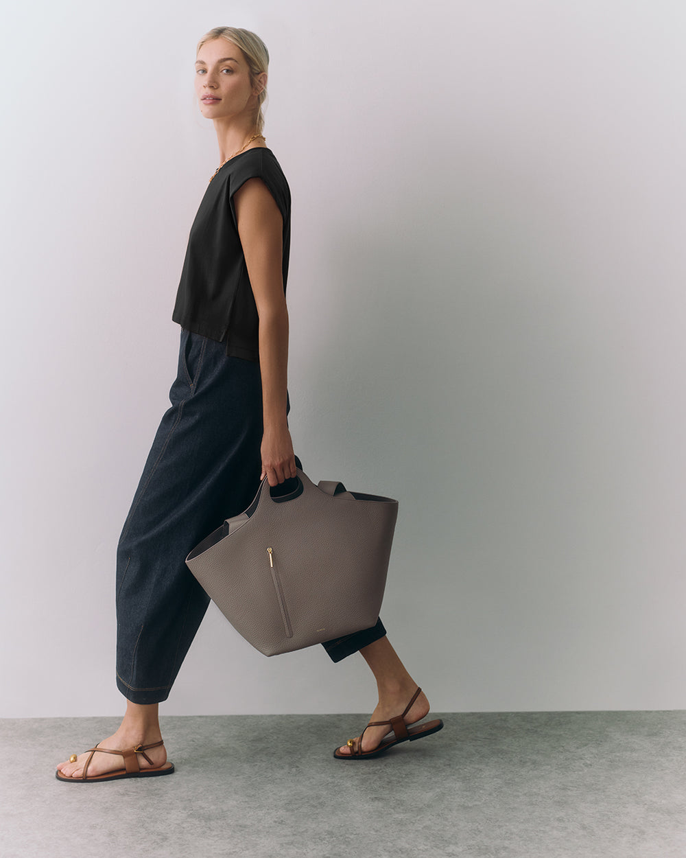 Person walking with a large handbag wearing sandals and casual outfit.